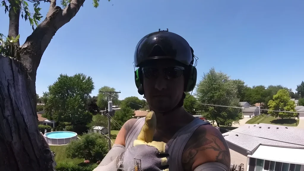 Rob Burgund in climbing helmet on a crane-assisted removal near power lines (from his job video)